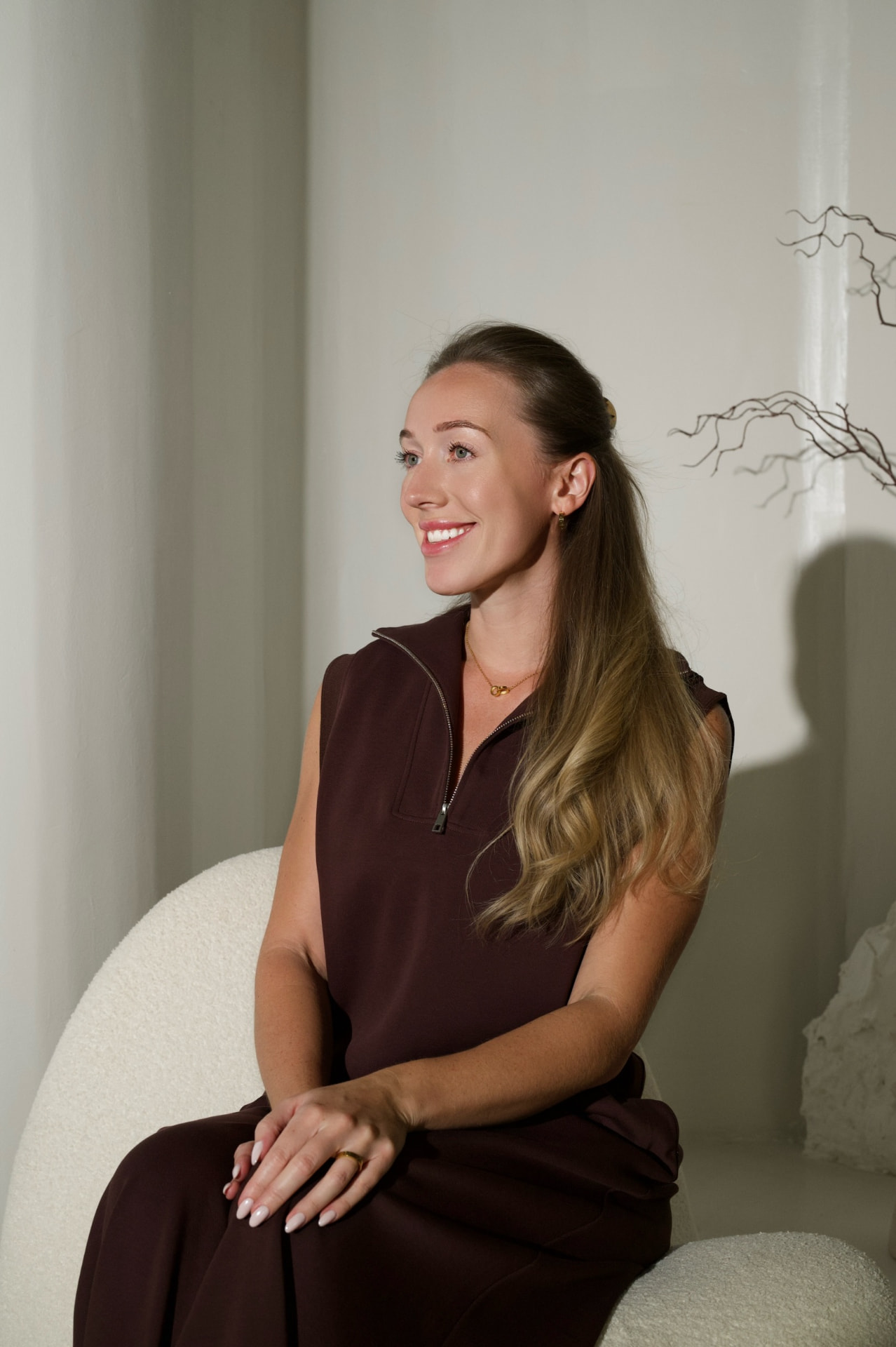 Chloe seated in a bouclé chair in the private space, smiling in soft daylight